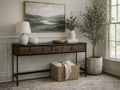 A three-drawer industrial console table with a dark charcoal top, medium-toned wood drawer fronts, and a slim black metal frame.