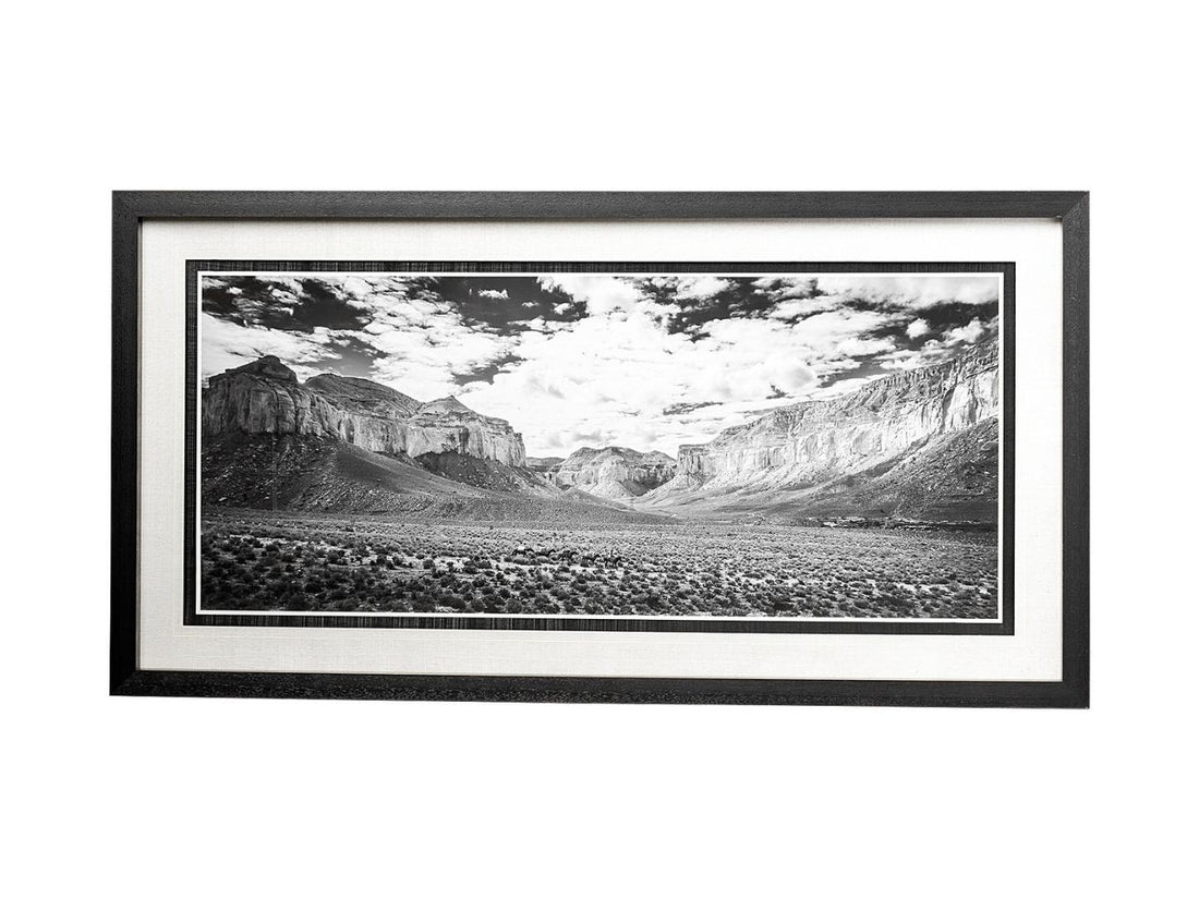 Framed black and white landscape print of a canyon with mountains and clouds.