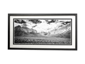 Framed black and white landscape print of a canyon with mountains and clouds.