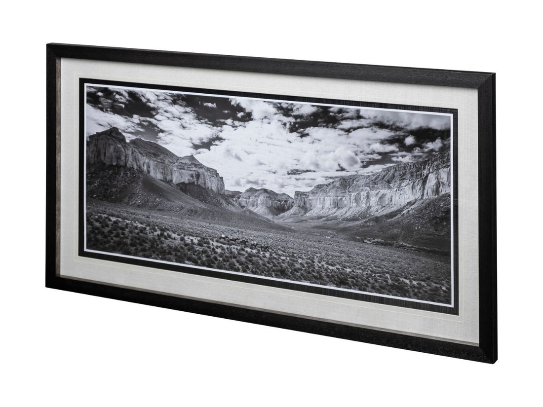 Framed black and white landscape print of a canyon with mountains and clouds.