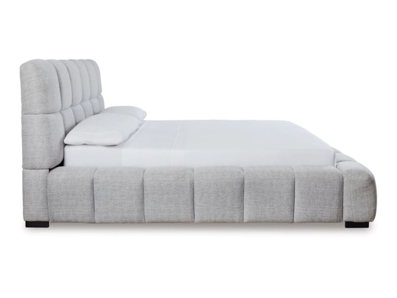 Side profile of light gray upholstered bed with low padded rails.