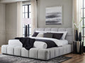 Light gray upholstered bed styled in a bright, modern bedroom.