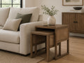 Nesting accent tables with warm wood frames and woven cane side panels, styled beside a cream sofa in a bright contemporary living room.