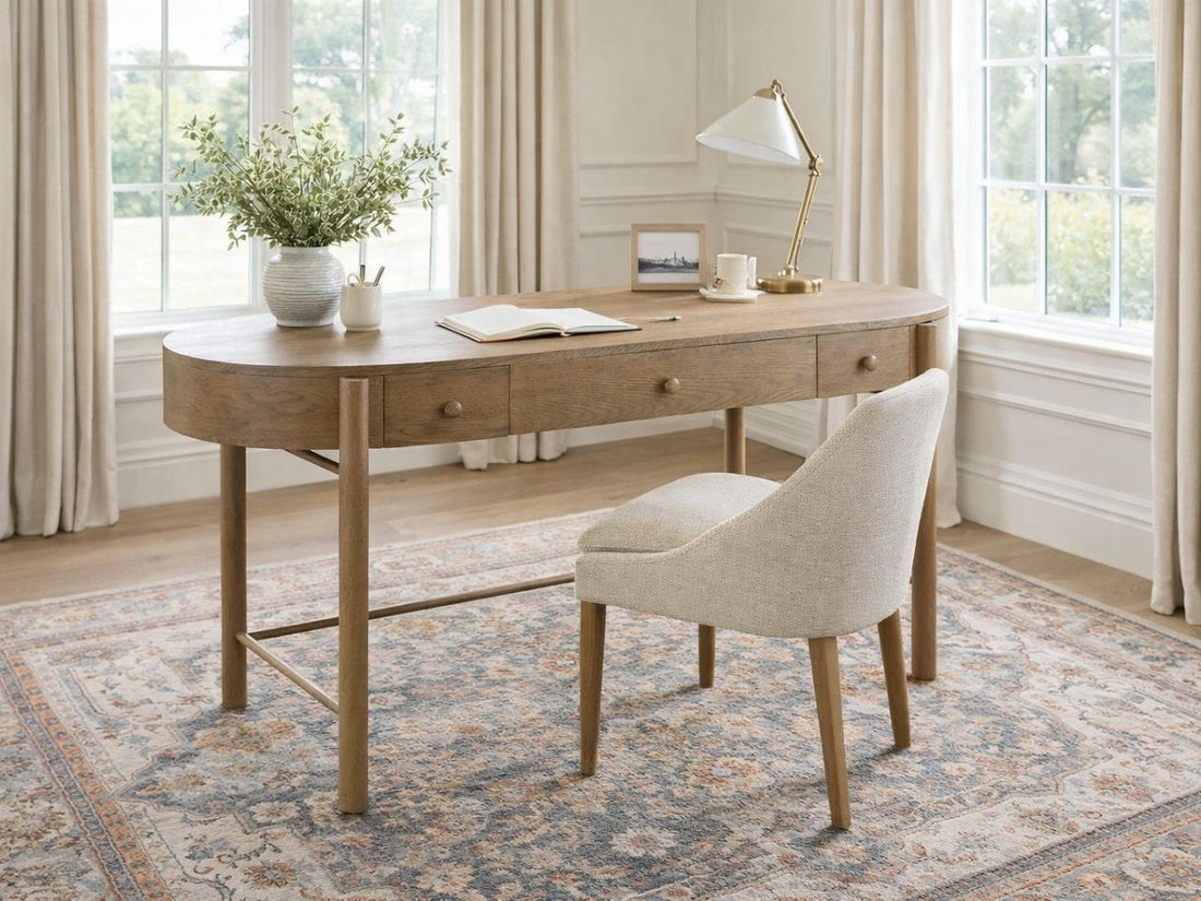 Brown oval wood writing desk with drawers in a bright home office.