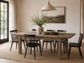 Rustic reclaimed wood dining table with six black spindle-back chairs in a warm, modern farmhouse dining room.