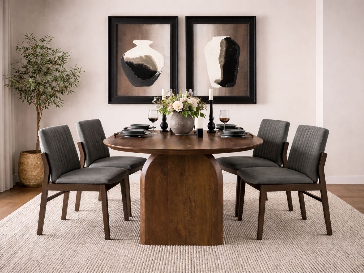 Oval dark wood dining table with sculptural pedestal base, paired with gray upholstered dining chairs in a modern dining room.
