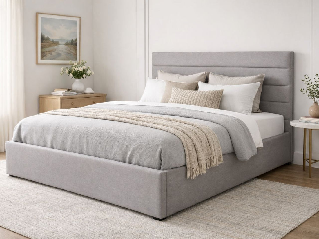 A light gray upholstered bed with a padded headboard in a calm, modern bedroom.