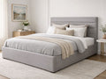 A light gray upholstered bed with a padded headboard in a calm, modern bedroom.