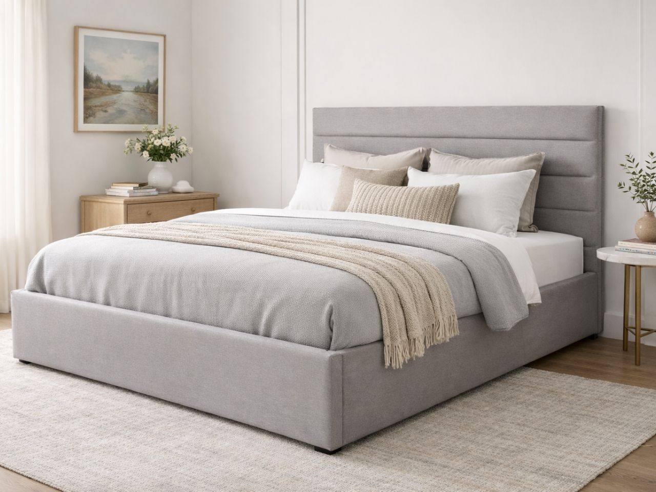 A light gray upholstered bed with a padded headboard in a calm, modern bedroom.
