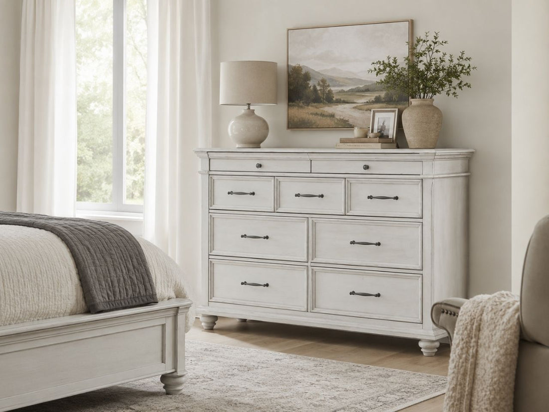 Distressed white dresser with classic framed drawers, dark metal pulls, turned feet, and vintage farmhouse styling.