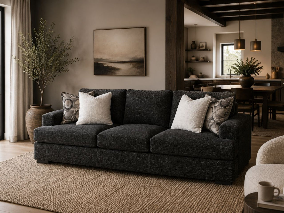 Modern charcoal grey sofa with plush cushions in a luxurious living room. 
