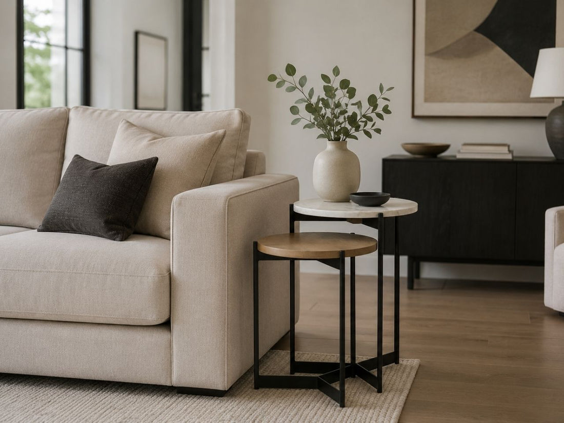 Nested marble and wood side tables beside a cream sofa in a contemporary living room.