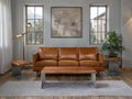 A modern living room featuring a leather sofa flanked by matching wood-and-metal side tables, with a coordinating coffee table centered on a textured area rug.