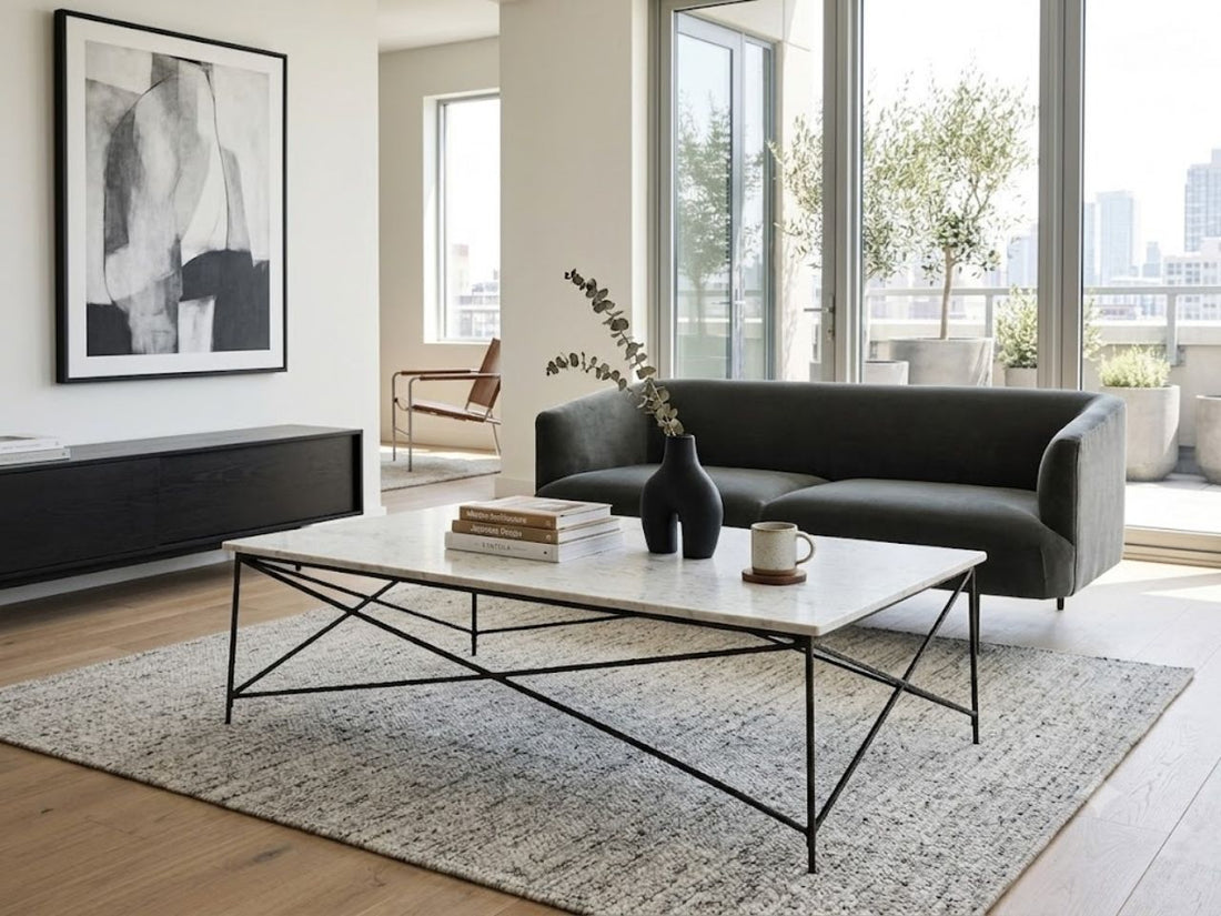 Modern marble-top coffee table with a sleek geometric metal base, styled in a bright contemporary living room.