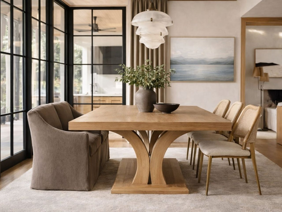 Wood pedestal dining table with mixed seating in a bright modern dining room.