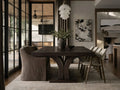 A dark wood rectangular dining table with upholstered cream and dark chairs with a rug and vase. 