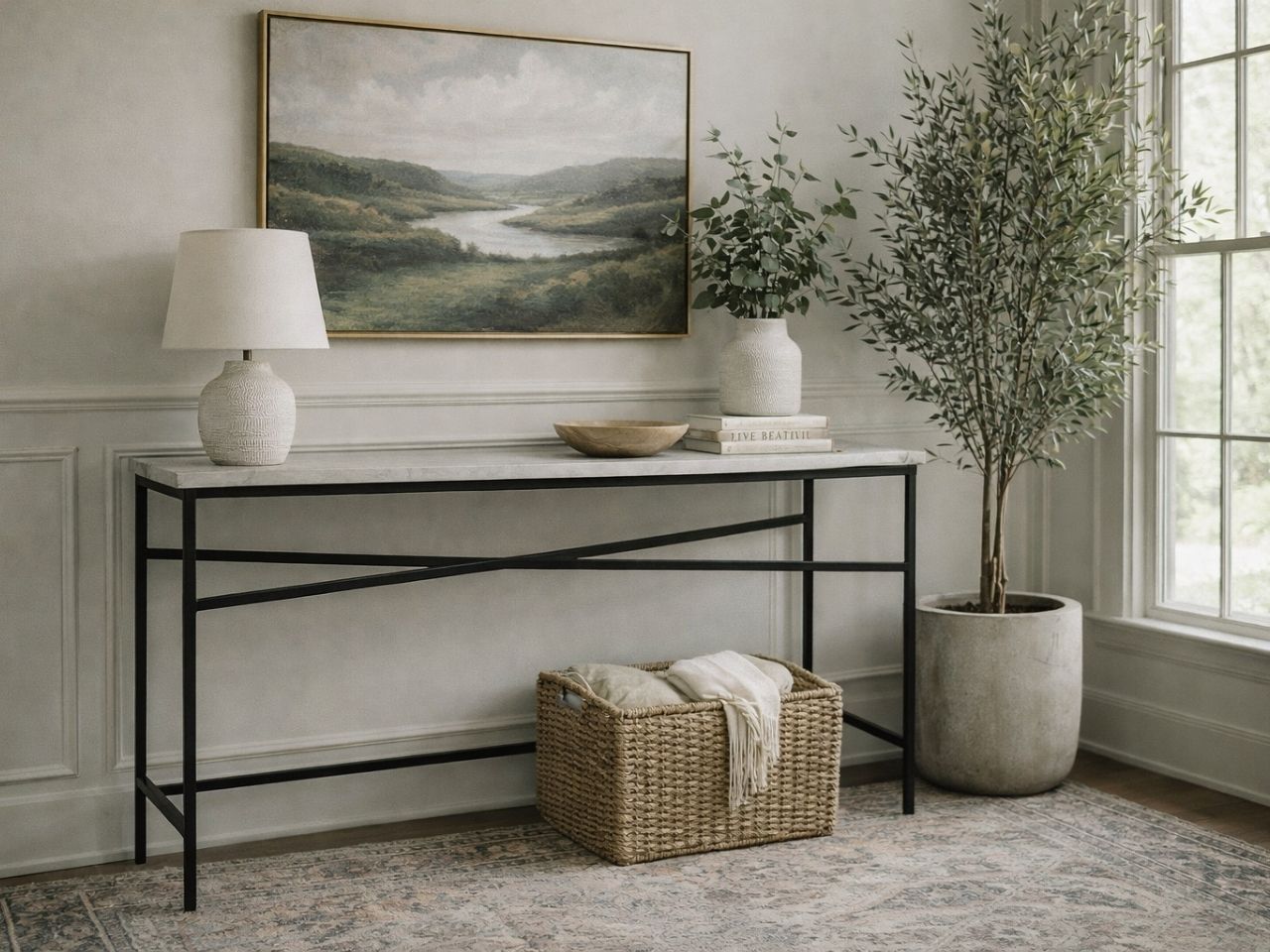 A minimalist console table with a rectangular white marble top and a black metal frame featuring an X-crossbar design.