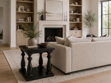 Black wood end table beside a cream sofa in a bright modern living room.