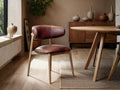 Tobacco leather dining chair styled beside a wood table in a warm, modern dining room.