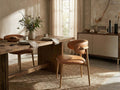 Tan upholstered dining chair at a wooden dining table in a warm, styled dining room.