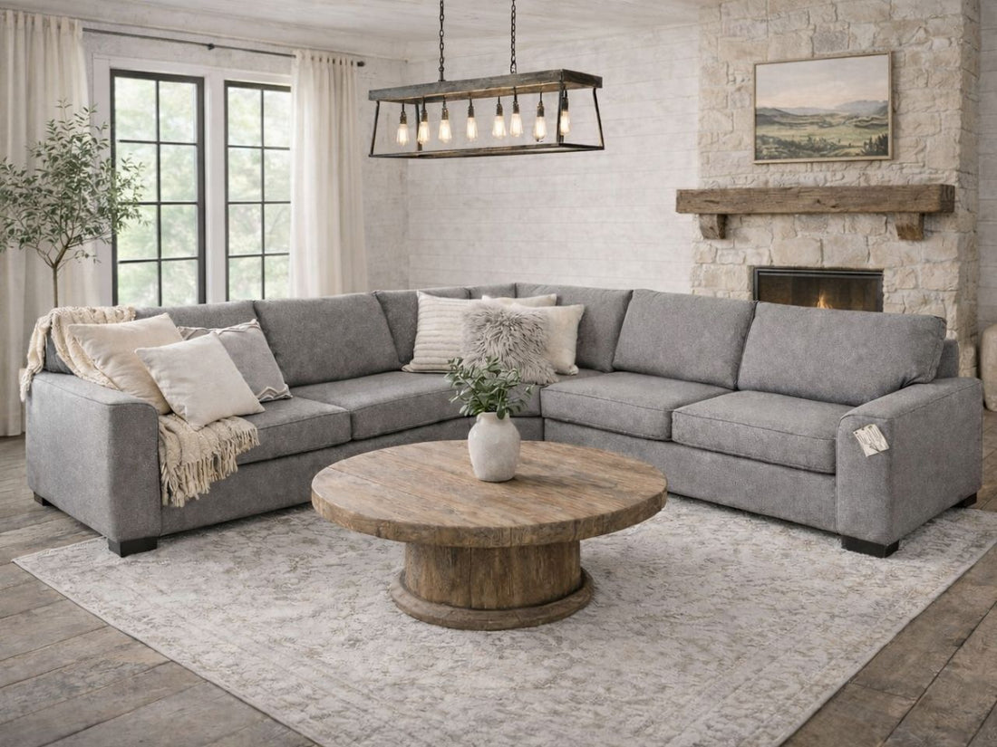Gray upholstered sectional sofa styled in a spacious living room with a round wood coffee table and fireplace.
