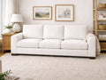 Neutral living room featuring a cream sofa, soft textured rug, and simple framed wall art.