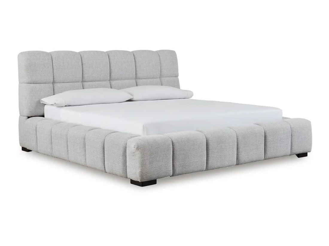 A light upholstered bed with a channel-tufted frame in a bright, serene bedroom.