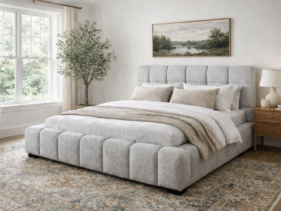 A light upholstered bed with a channel-tufted frame in a bright, serene bedroom.
