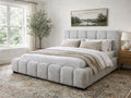 A light upholstered bed with a channel-tufted frame in a bright, serene bedroom.