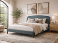 Upholstered bed with rounded headboard styled in a bright bedroom with wood nightstands.