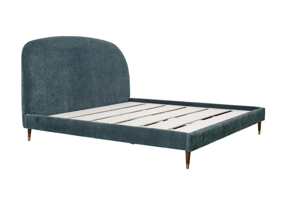 Upholstered bed with rounded headboard styled in a bright bedroom with wood nightstands.