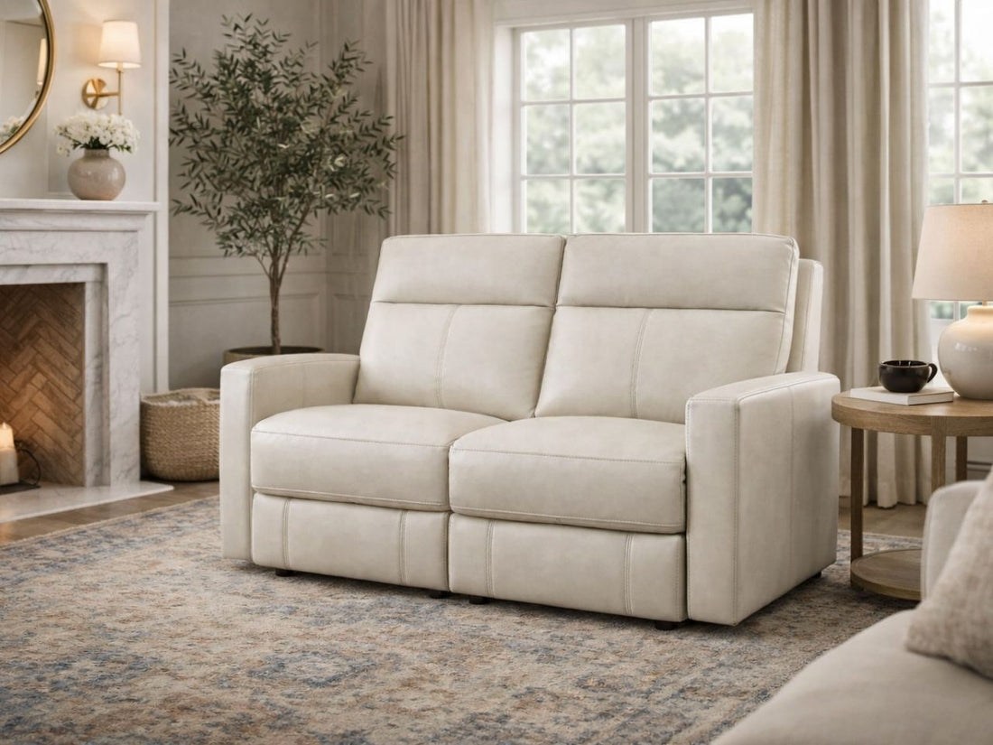 Warm brown reclining loveseat upholstered in genuine or faux leather, placed in a cozy, classic living room setting.