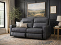 Modern dark gray reclining loveseat upholstered in smooth leather or leather-look fabric, set in a contemporary living room with dark paneled walls.