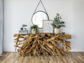 Natural wood root console table styled against a light wall in a home interior.