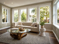 Round glass coffee table with a natural wood root base, styled in a bright living room with a curved sofa and large windows.