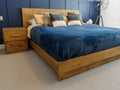 A rustic wood bed styled with layered bedding in a cozy, modern bedroom.
