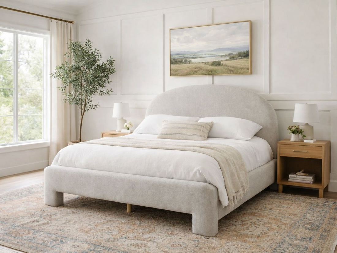 Upholstered bed with a rounded headboard styled in a bright, neutral bedroom.