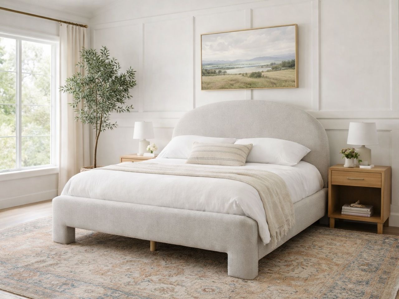 Upholstered bed with a rounded headboard styled in a bright, neutral bedroom.