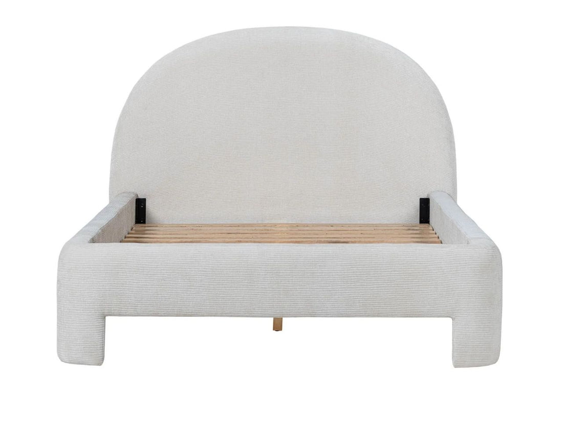 Upholstered bed with a rounded headboard styled in a bright, neutral bedroom.
