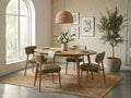 Oval wooden dining table styled with green chairs in a bright, modern dining room.