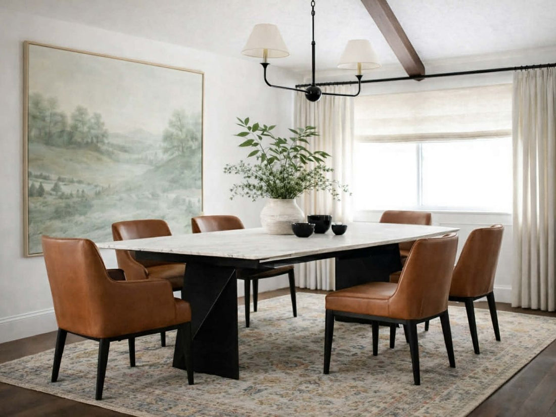 Rectangular dining table with a light stone top and black sculptural legs, styled with brown leather dining chairs in a modern dining room.