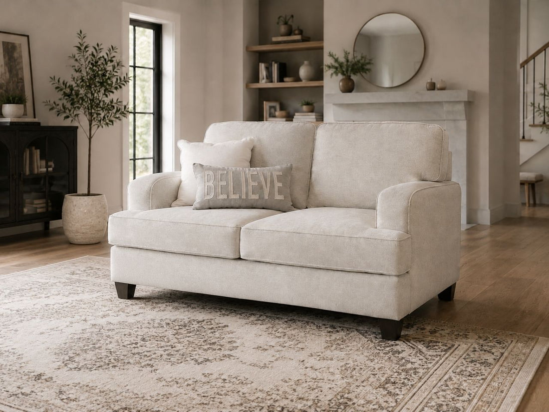 Neutral fabric loveseat with plush cushions, track arms, and dark wood legs in a cozy modern living room.