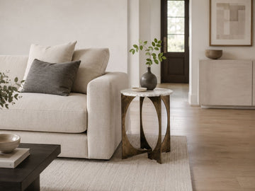 Round marble side table with a metal base beside a cream sofa.