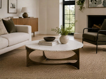 Round coffee table with a white stone-look top and dark wood base styled in a cozy modern living room.