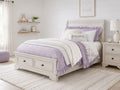 Whitewashed sleigh bed with built-in footboard storage drawers, perfect for a cozy kids' bedroom.