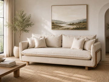 Cream upholstered sofa with wood accents and plush cushions in a warm, modern living room.