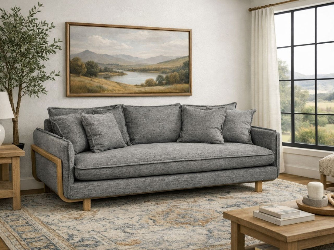 A gray upholstered sofa with wooden accents in a cozy, modern living room.