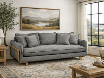 A gray upholstered sofa with wooden accents in a cozy, modern living room.