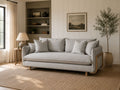 Light gray upholstered sofa with wood accents and plush cushions in a cozy living room.