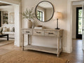 Rustic farmhouse console table with drawers and lower shelf styled with a round mirror, lamp, and neutral décor.